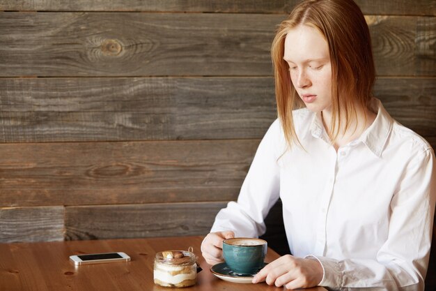 Femme rousse assise dans un café