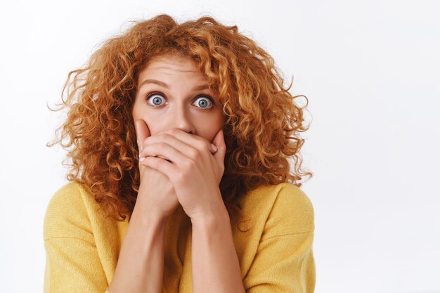 femme rousse aux cheveux bouclés en pull jaune, haletant secoué avec des yeux écarquillés, témoin du désastre effrayé faire du bruit