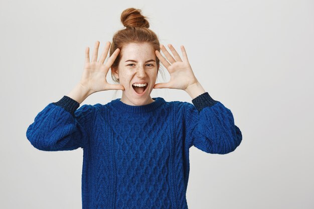 Femme rousse charismatique excitée souriant et montrant les mains près du visage