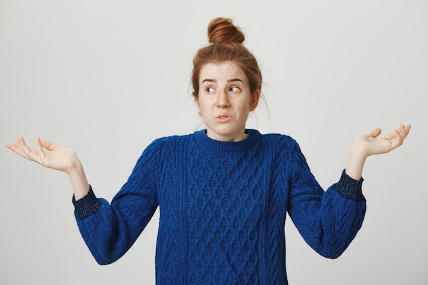 Femme rousse confuse haussant les épaules et regardant ailleurs perplexe