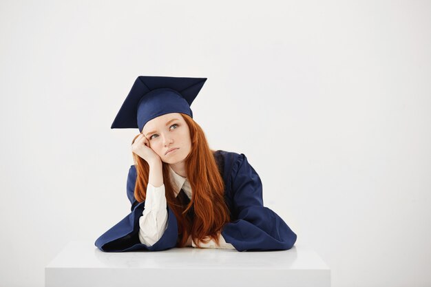 Femme rousse diplômée en pensée de manteau assis.