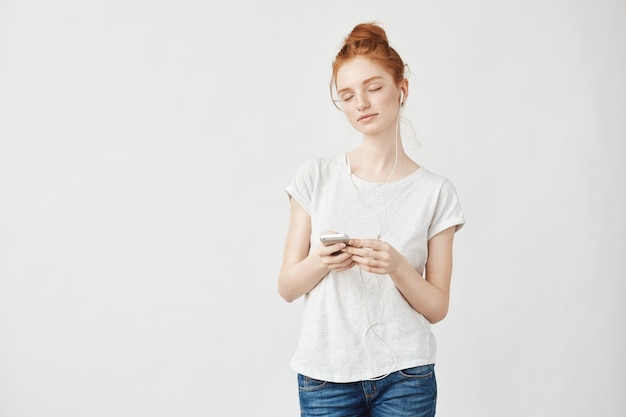 femme rousse, écouter de la musique dans les écouteurs en appréciant.