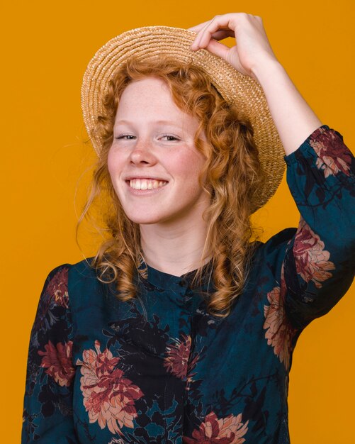 Femme rousse frisée à la mode en studio avec fond coloré