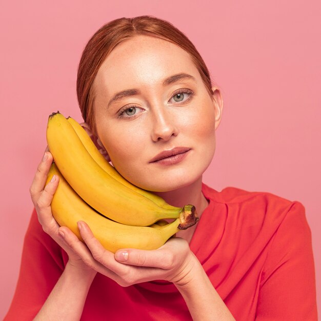 Femme rousse posant à côté de bananes