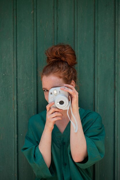 Femme rousse utilisant un appareil photo vintage