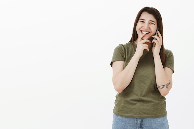 Femme s'amusant ayant une conversation hilarante décontractée avec des amis en parlant via un smartphone tenant un téléphone portable près de l'oreille en riant et en souriant tenant la main près de la bouche