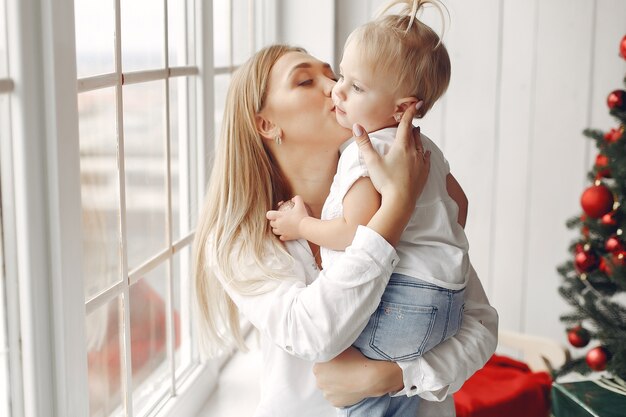 La femme s'amuse à préparer Noël. Mère en chemise blanche joue avec sa fille. La famille se repose dans une salle de fête.