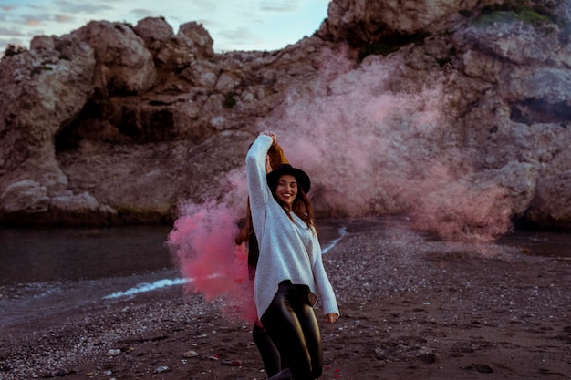 Photo gratuite femme s'amuser avec une bombe de fumée au bord de la mer