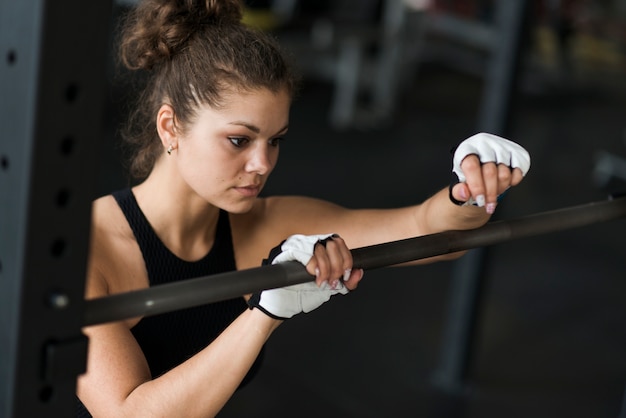 Femme s&#39;appuyant sur la barre dans la salle de gym