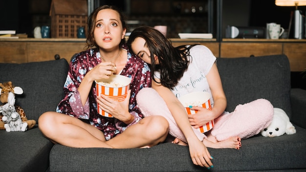 Photo gratuite femme s'appuyant sur l'épaule de son amie en regardant la télévision