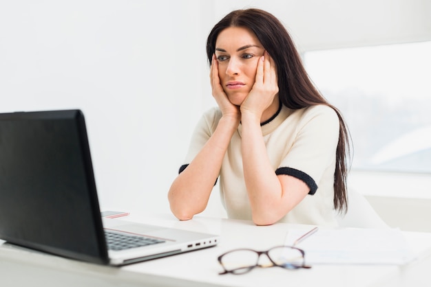 Femme s&#39;ennuie assis à table avec un ordinateur portable