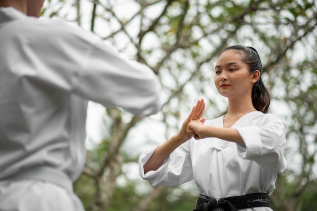 Photo gratuite femme s'entraînant au taekwondo en plein air dans la nature
