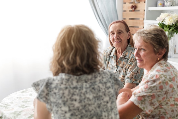 Femme avec sa mère et sa grand-mère assis ensemble dans la cuisine