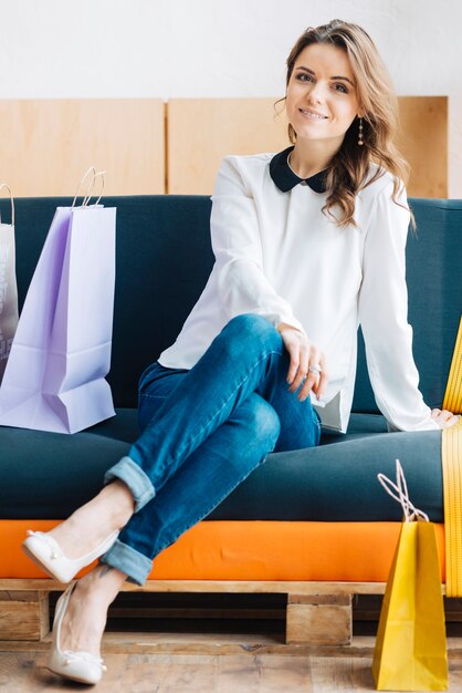 Femme avec des sacs en papier sur le canapé