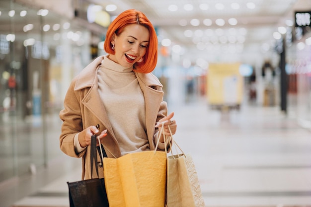 Femme avec des sacs à provisions faisant des achats dans le centre commercial