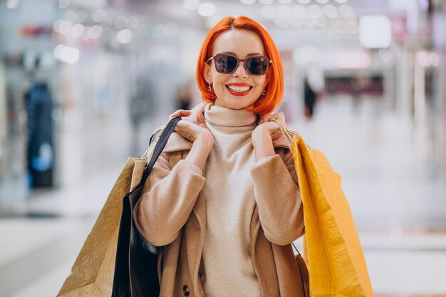 Femme avec des sacs à provisions faisant des achats dans le centre commercial