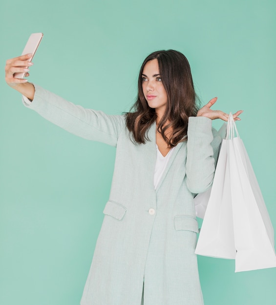 Femme avec des sacs à provisions prenant un selfie