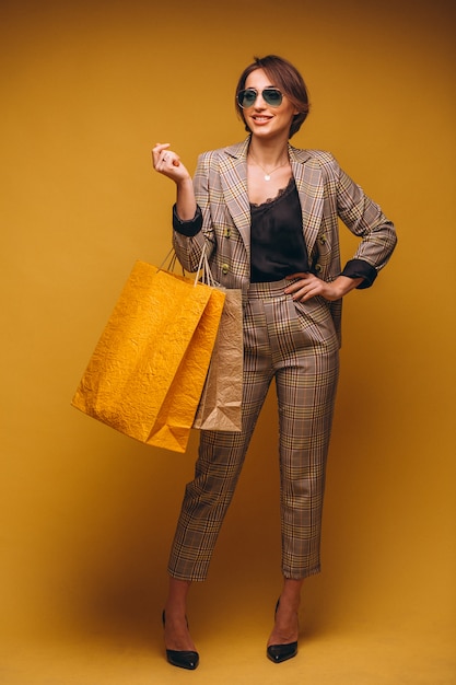 Femme avec des sacs à provisions en studio sur fond jaune isolé