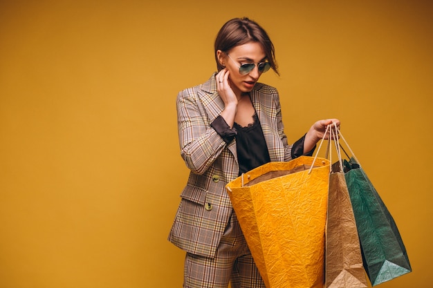 Femme avec des sacs à provisions en studio sur fond jaune isolé