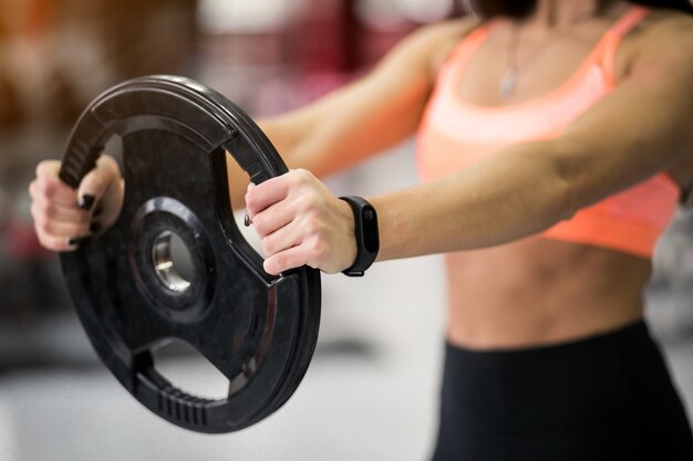 Femme à la salle de gym avec plaque de poids