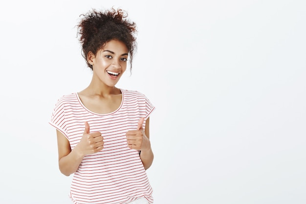 Femme satisfaite avec une coiffure afro qui pose en studio