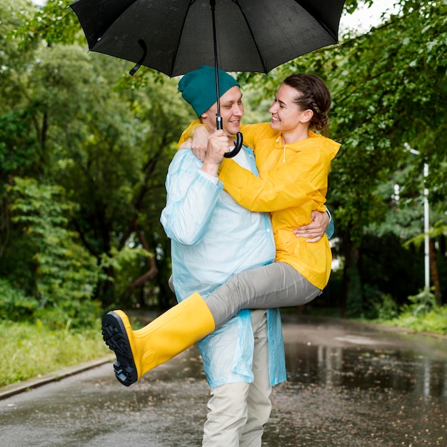 Femme sautant par-dessus son mari sous le parapluie