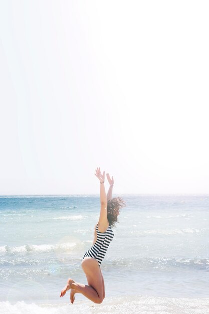 Femme sautant sur la plage