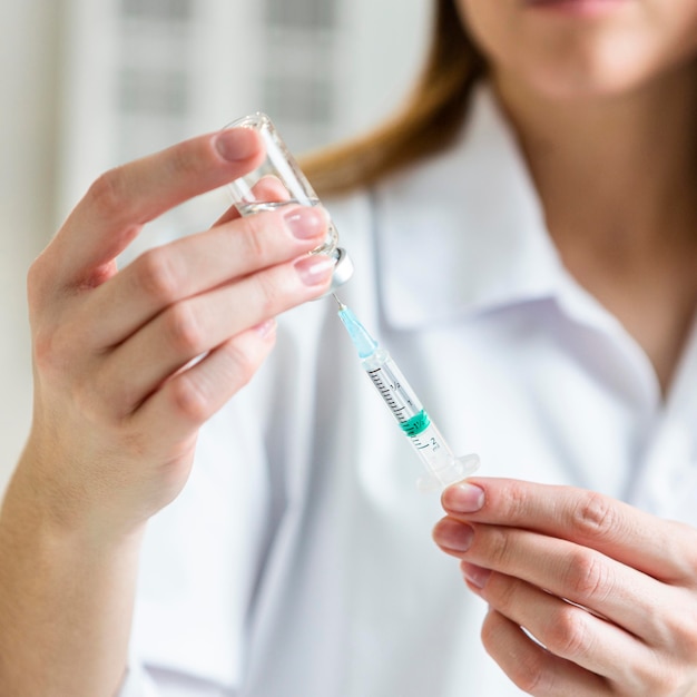 Femme scientifique défocalisée avec des lunettes de sécurité tenant une seringue avec un vaccin