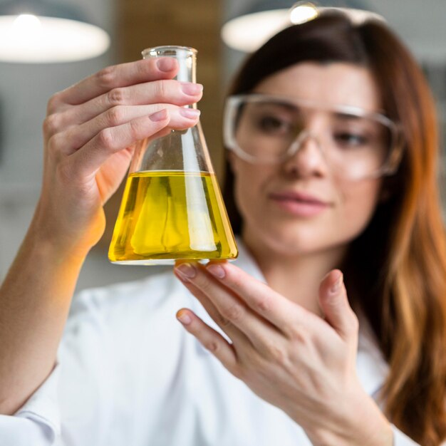 Femme scientifique défocalisée tenant un tube à essai