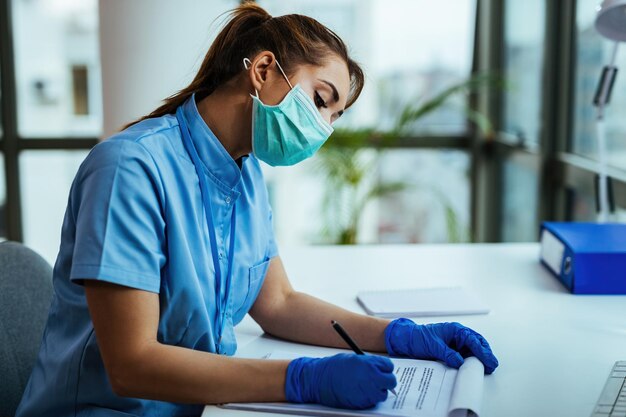 Femme scientifique faisant de la recherche médicale et écrivant des données tout en travaillant pendant une épidémie de virus dans un hôpital