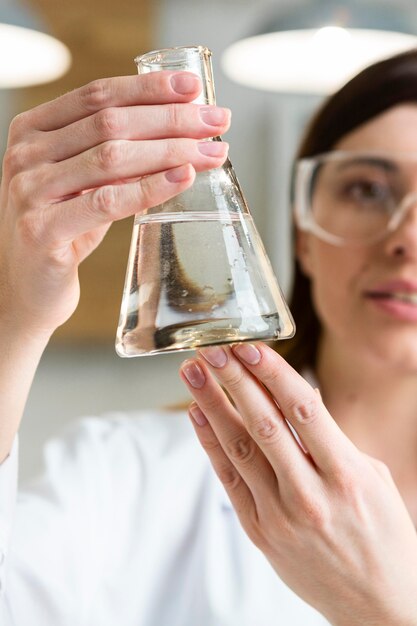 Femme scientifique avec des lunettes de sécurité tenant un tube à essai dans le laboratoire