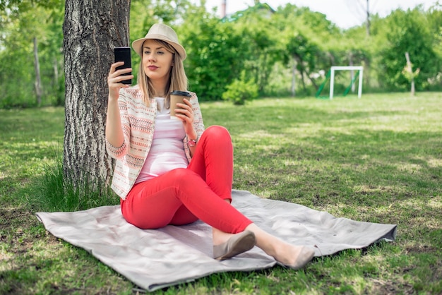 Femme se détendant au parc et utilisant un téléphone intelligent.