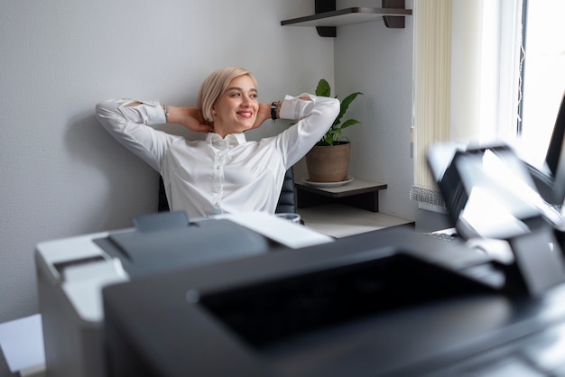 Femme se détendre au bureau à côté de l'imprimante