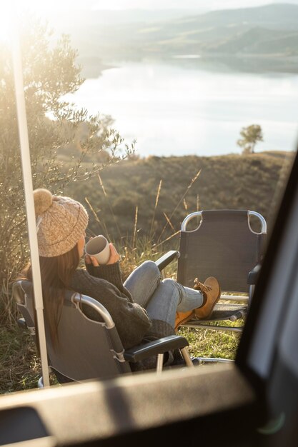 Femme se détendre à côté de la voiture lors d'un road trip