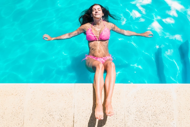 Femme se détendre dans la piscine avec les yeux fermés