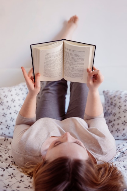 Photo gratuite femme se détendre sur le lit avec un livre