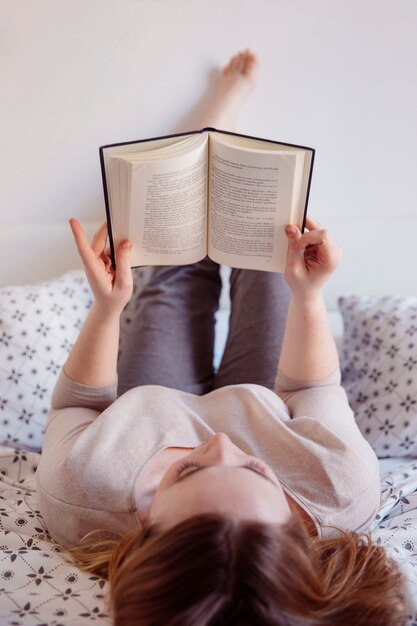 Femme se détendre sur le lit avec un livre