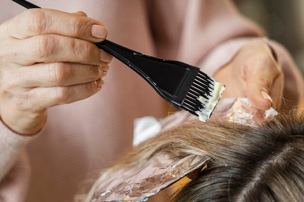 Femme se fait teindre les cheveux à la maison par une esthéticienne