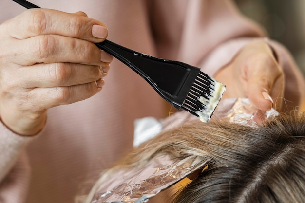 Femme se fait teindre les cheveux à la maison par une esthéticienne