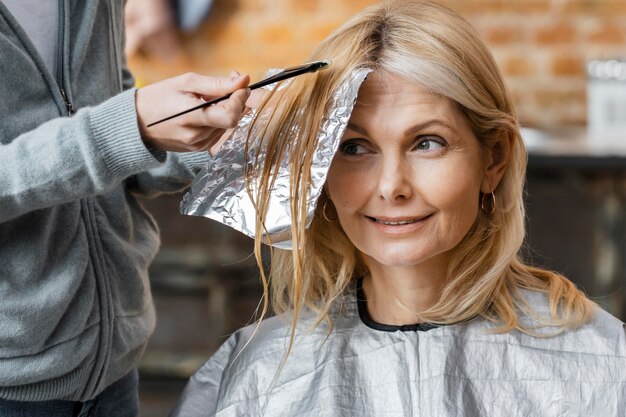 Femme se fait teindre les cheveux par un coiffeur à la maison