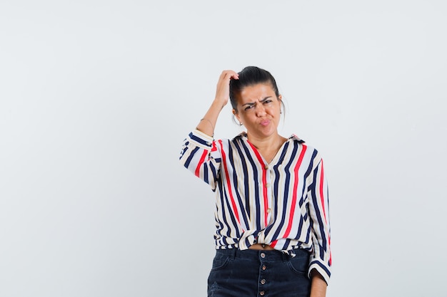 Femme se gratter la tête en chemise, jupe et à hésitant