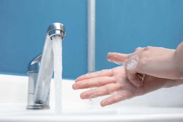 Femme se lavant soigneusement les mains avec du savon et du désinfectant, gros plan. Prévention de la propagation du virus de la pneumonie, protection contre la pandémie de coronavirus. Hygiène, sanitaire, propreté, désinfection. Sécurité.