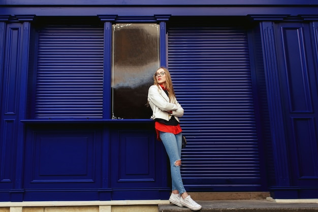 Photo gratuite femme se penche vers une porte bleue se tenant dans la rue