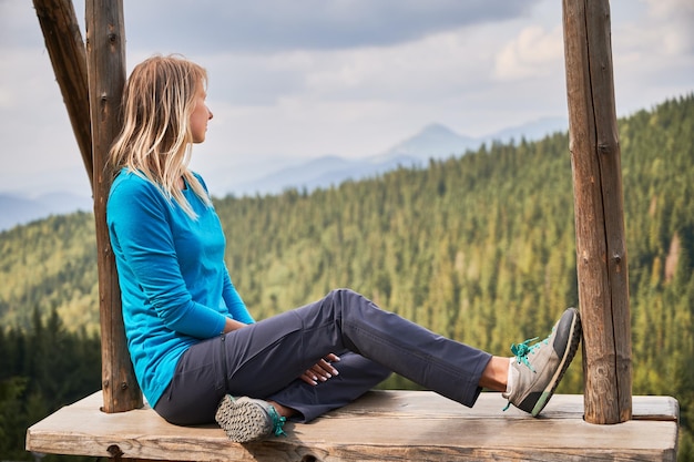 Femme se reposant dans une grande balançoire à l'extérieur dans les montagnes