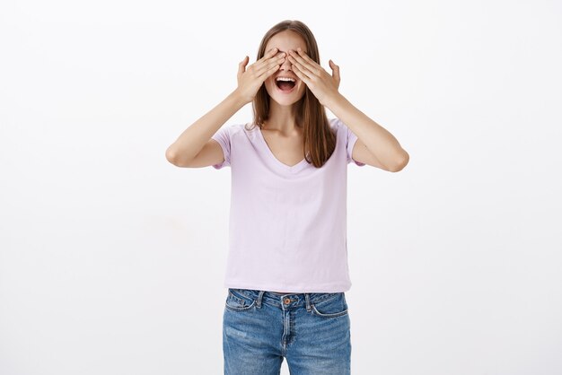 Femme se sentant amusé couvrant les yeux avec les mains, sourire excité à proximité décontractée en attente d'une surprise impressionnante