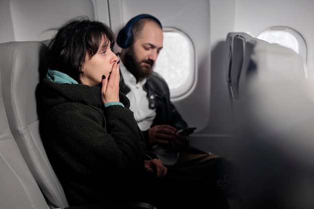 Photo gratuite femme se sentant tendue et effrayée par le décollage de l'avion, ayant peur de voler à l'étranger. voyager avec des compagnies aériennes internationales pour partir à l'aventure en vacances, vol commercial.