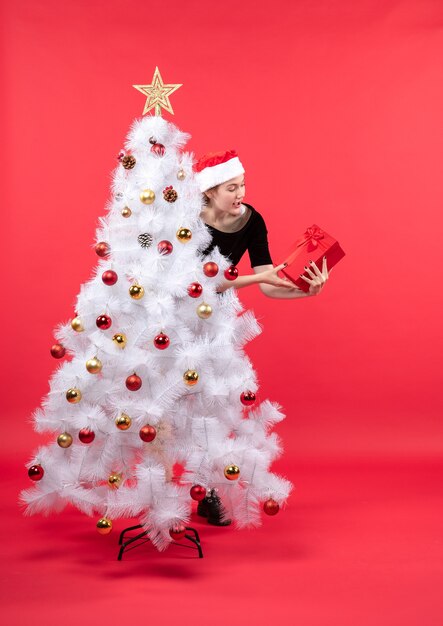 Une femme se tient à côté du sapin de Noël