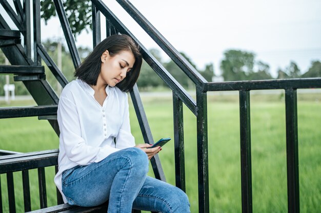 Femme, séance, échelle, regarder téléphone intelligent, avoir, stress