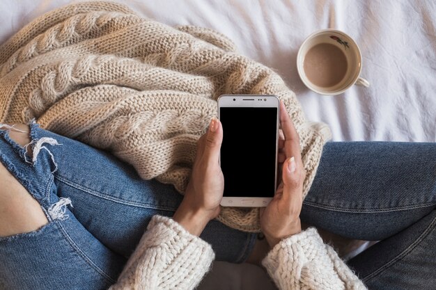 Femme, séance lit, à, téléphone, et, tasse café