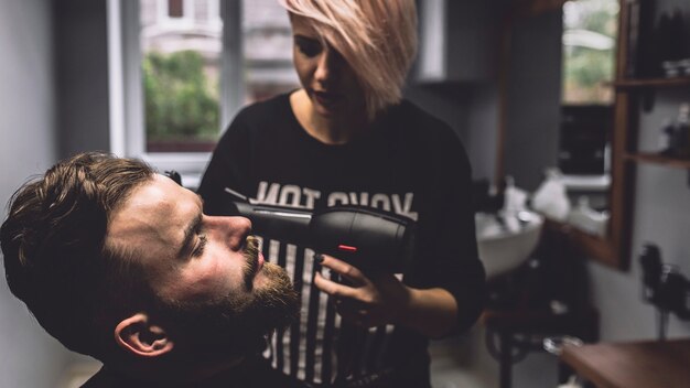 Femme avec sèche-cheveux et client dans le salon